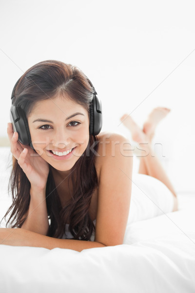 A close up picture of a  smiling woman with her headphones on, with her hand on them, while her legs Stock photo © wavebreak_media