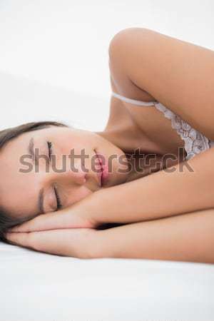 A woman smiling as she lies on her back with on hand on her stomach and the other under her head. Stock photo © wavebreak_media