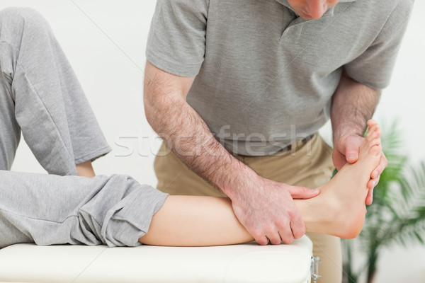 Doctor examining the foot of a woman while standing in a well-lit room Stock photo © wavebreak_media