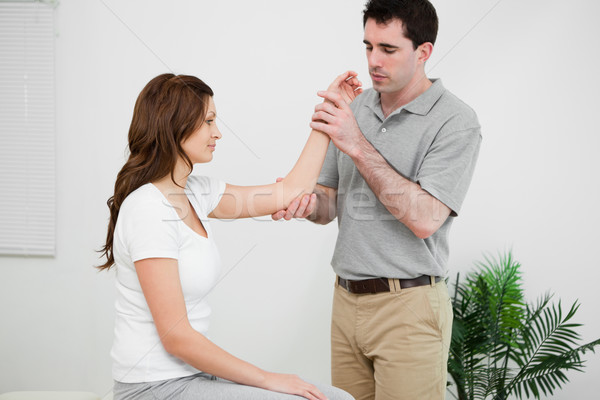 Serious physiotherapist looking at the arm of a woman in a medical room Stock photo © wavebreak_media