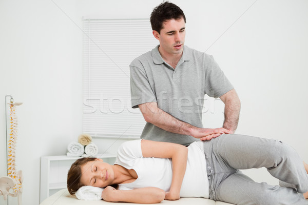 Stock photo: Doctor pressing his hands on the hip of his patient in a room