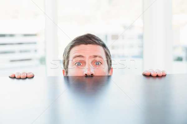 Nervous businessman peeking over desk Stock photo © wavebreak_media