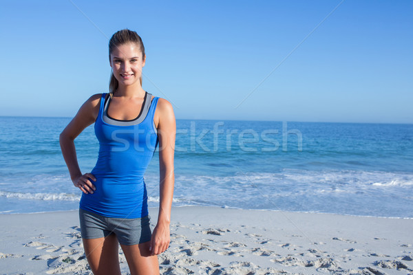 Uśmiechnięty dopasować kobieta patrząc kamery plaży Zdjęcia stock © wavebreak_media