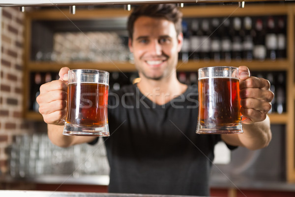 Handsome barman holding a pint of beer Stock photo © wavebreak_media