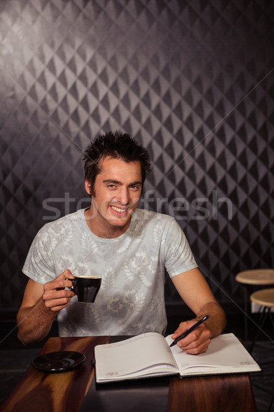 Smiling hipster having coffee and writing in planner Stock photo © wavebreak_media