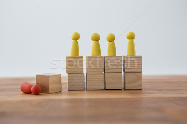 Yellow Figurines on wooden blocks in a row and red figurine fallen on ground Stock photo © wavebreak_media