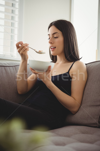 улыбающаяся женщина еды завтрак сидят диван женщину Сток-фото © wavebreak_media
