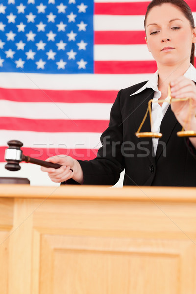 Portrait of a cute judge knocking a gavel and holding scales of justice with an American flag in the Stock photo © wavebreak_media