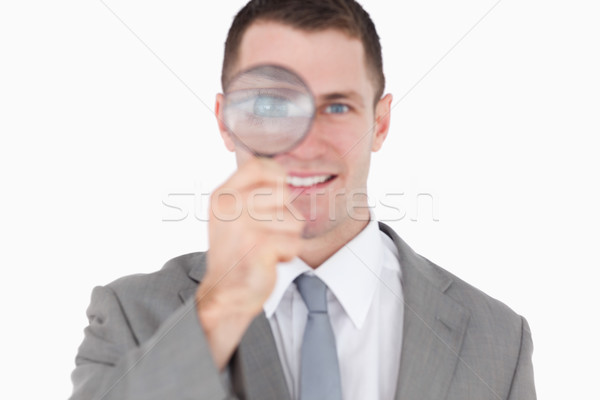 Young businessman looking through a magnifying glass against a white background Stock photo © wavebreak_media