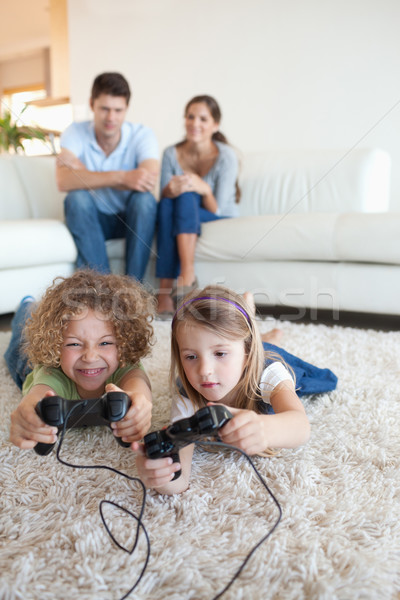 Stock photo: Portrait of children playing video games while their parents are watching in their living room