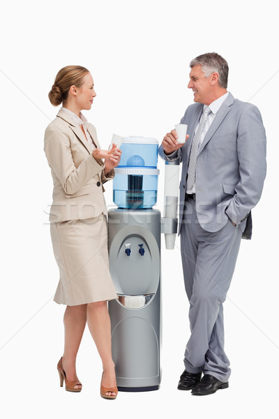 Business people laughing next to the water dispenser against white background Stock photo © wavebreak_media