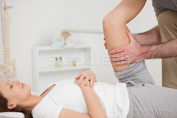 Stock photo: Physiotherapist holding the thigh of a patient in a room