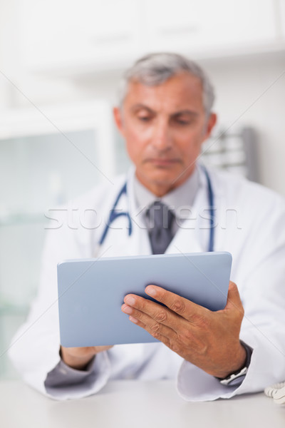 Stock photo: Doctor holding a tablet computer while using it in a medical office