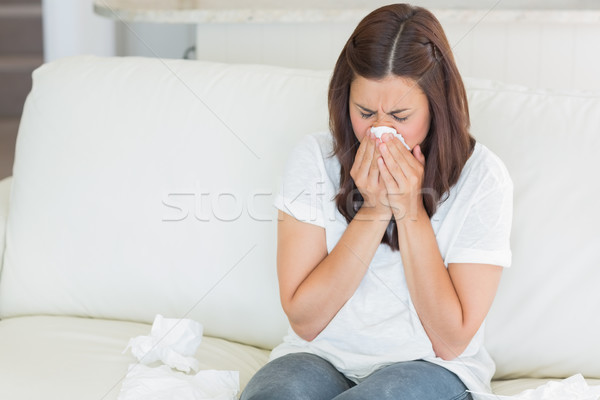 Sick woman sneezing on sofa Stock photo © wavebreak_media