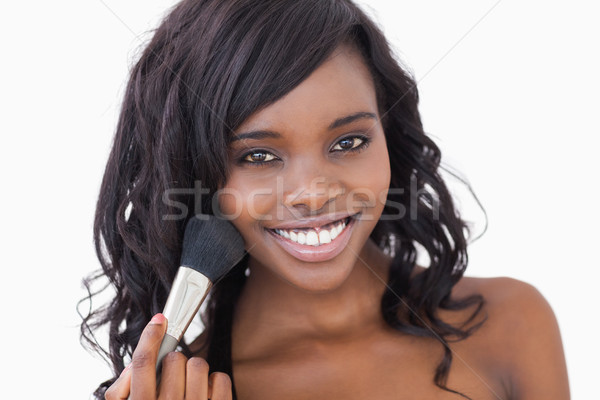 Woman smiling while holding a makeup brush against white background Stock photo © wavebreak_media