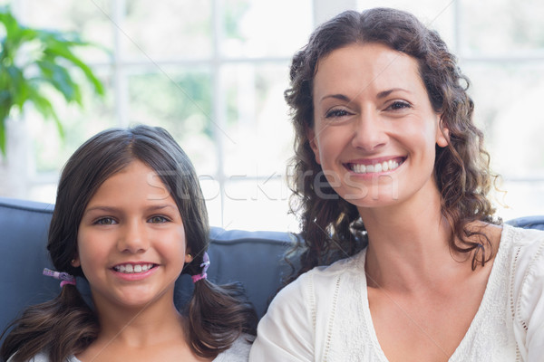 Happy mother and daughter sitting on the couch and smiling at ca Stock photo © wavebreak_media