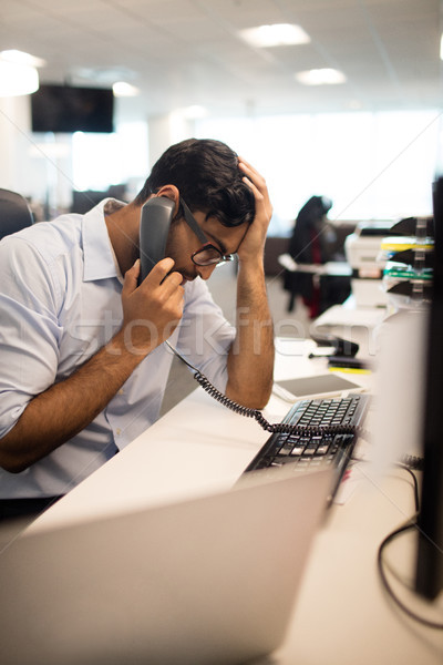 Tensed businessman talking on land line at desk Stock photo © wavebreak_media