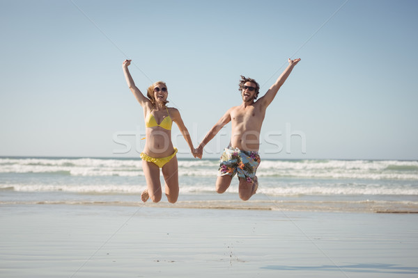 Cheerful couple holding hands while jumping at beach Stock photo © wavebreak_media