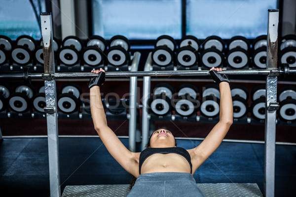 Fit woman lifting barbell while lying on bench  Stock photo © wavebreak_media