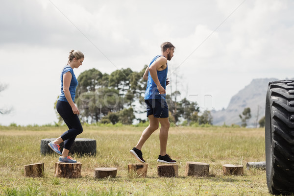 Fit woman and man running on wooden logs during obstacle course Stock photo © wavebreak_media