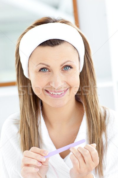 Bright young woman filing her nails smiling at the camera Stock photo © wavebreak_media