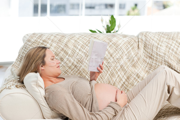 Foto stock: Concentrado · mulher · grávida · leitura · livro · sofá · casa