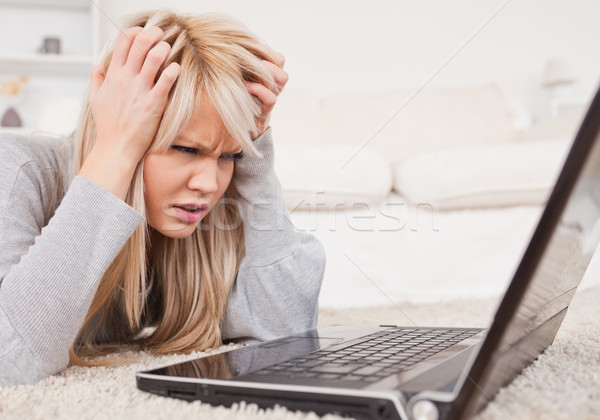 Attractive blond woman frustrated with her computer lying on a carpet in the living room Stock photo © wavebreak_media
