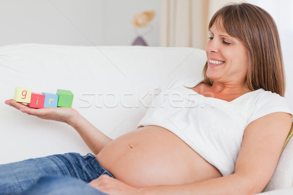 Beautiful pregnant woman playing with wooden blocks and having the word 'girl' written on her hand w Stock photo © wavebreak_media
