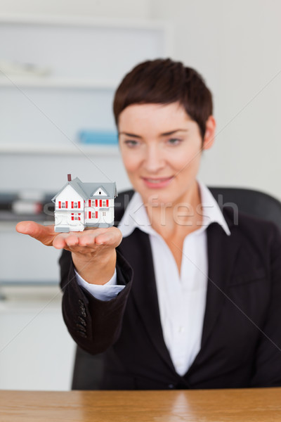 Portrait of a brunette showing a house miniature in her office Stock photo © wavebreak_media