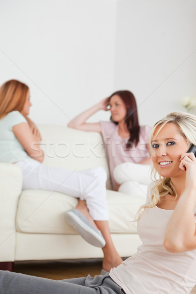 Cheerful woman with a phone separated from the others in a living room Stock photo © wavebreak_media