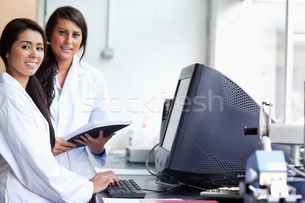 Smiling female scientist posing with a monitor while looking at the camera Stock photo © wavebreak_media