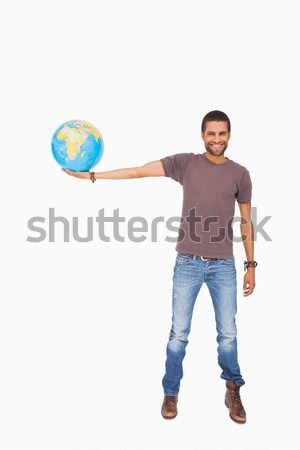 Smiling young salesman holding globe in his palm against a white background Stock photo © wavebreak_media