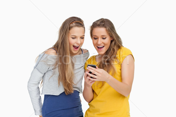 Deux jeunes femmes regarder smartphone blanche lecture [[stock_photo]] © wavebreak_media