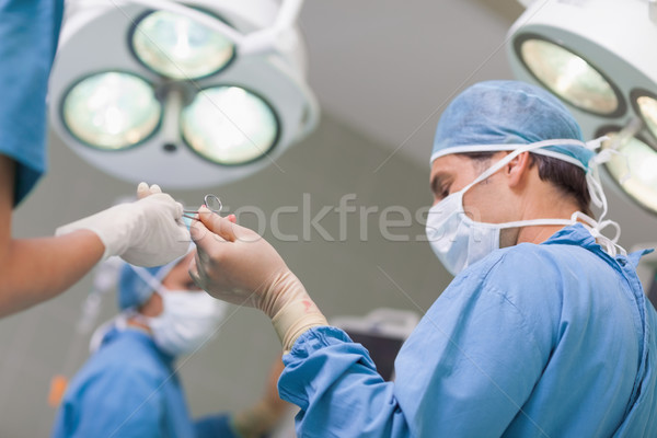 Doctor receiving a surgical scissor from a nurse in operating theater Stock photo © wavebreak_media