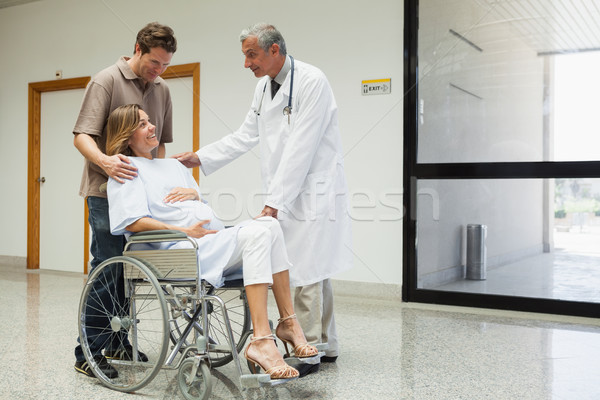 Pregnant woman with in wheelchair with partner talks to doctor in the hospital corridor Stock photo © wavebreak_media