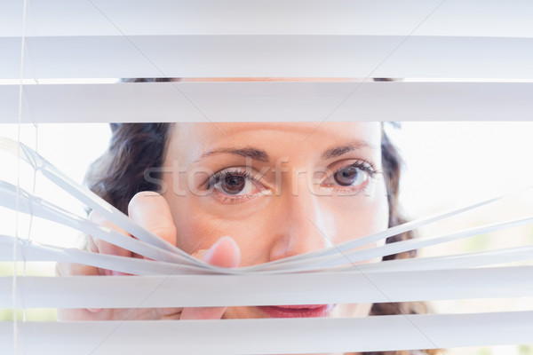 Curious woman looking through blinds Stock photo © wavebreak_media