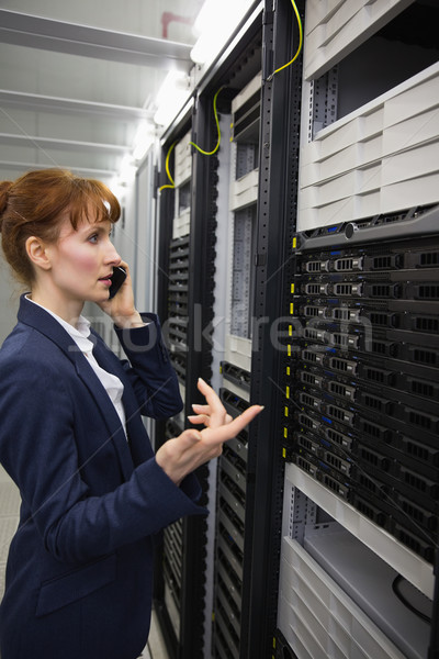 Pretty technician talking on phone while looking at server Stock photo © wavebreak_media