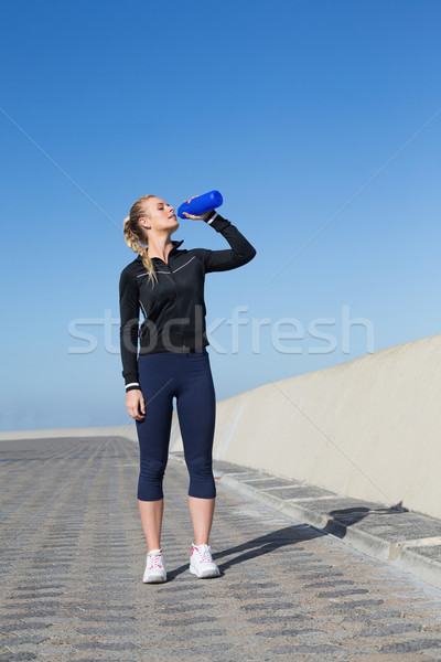 Stock photo: Fit blonde drinking water on the pier