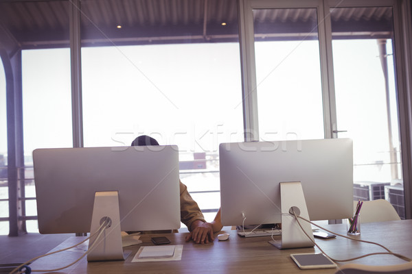 Businessman and businesswoman holding hands behind computers in office Stock photo © wavebreak_media