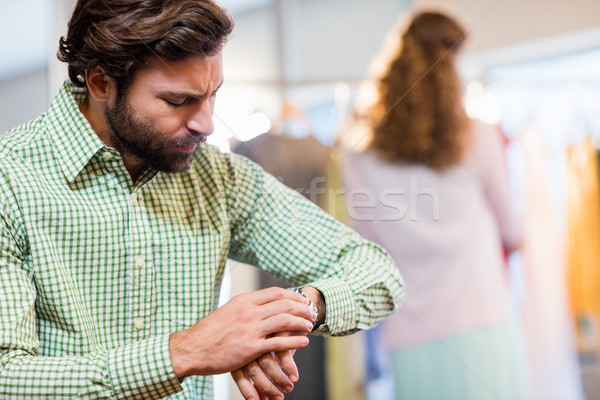 Stock photo: Bored man waiting his wife while woman by clothes rack