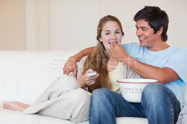 Happy couple watching television while eating popcorn in their living room Stock photo © wavebreak_media