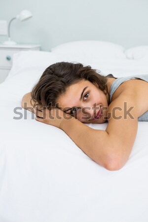A vertical shot of a woman in bed, smiling as she rests her head on the pillow. Stock photo © wavebreak_media