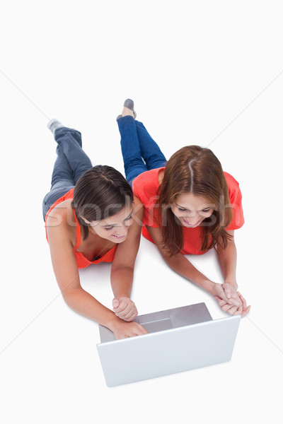 Smiling teenagers lying down while attentively looking at a computer Stock photo © wavebreak_media
