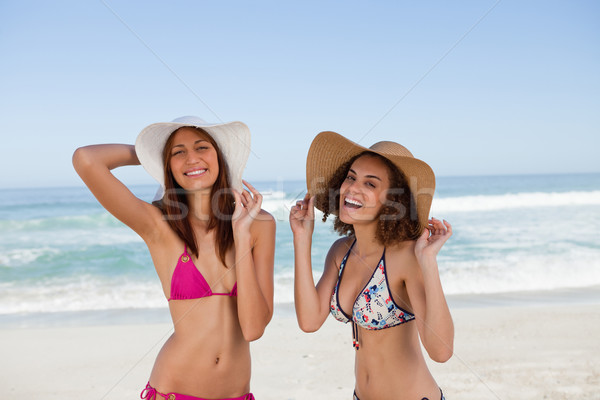 Stock photo: Happy young women sunbathing while standing in front of the sea side by side