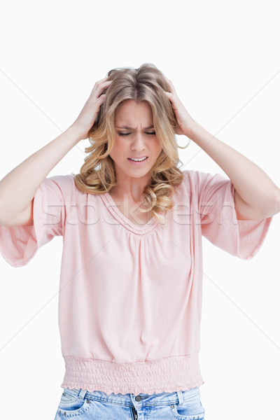 Stock photo: A frustrated woman with both her hands in her hair against a white background