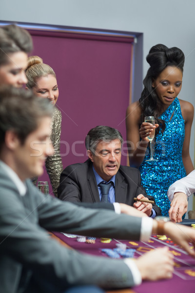 Stock photo: Women watching men placing bes on roulette