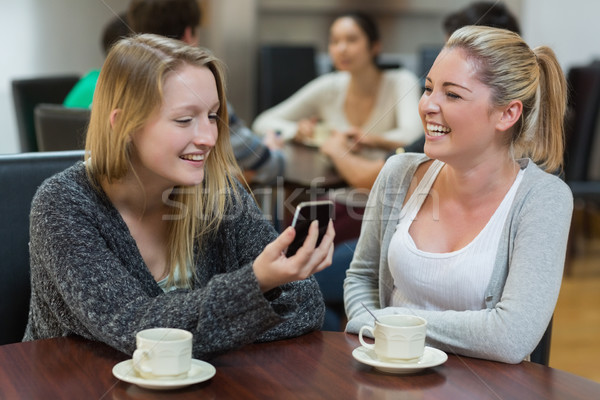 Vrouwen vergadering coffeeshop naar smartphone glimlachend Stockfoto © wavebreak_media