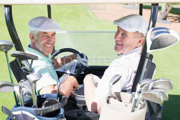 Golfing friends driving in their golf buggy smiling at camera Stock photo © wavebreak_media