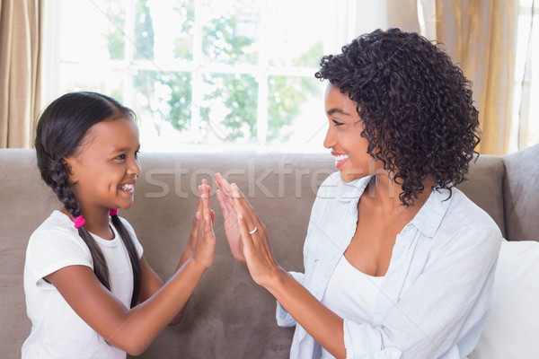 Pretty mother playing clapping game with daughter on couch Stock photo © wavebreak_media