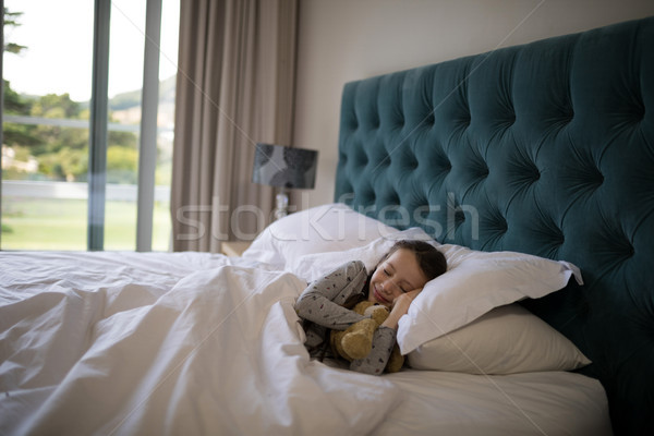 Girl sleeping on bed with teddy bear in bedroom Stock photo © wavebreak_media